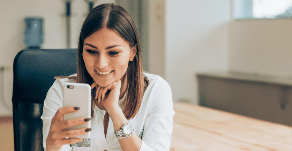 Woman looking at her phone and smiling, possibly to do with smartphone financing